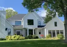 White modern farmhouse in Woodbury MN with new charcoal roof by Buildtec.