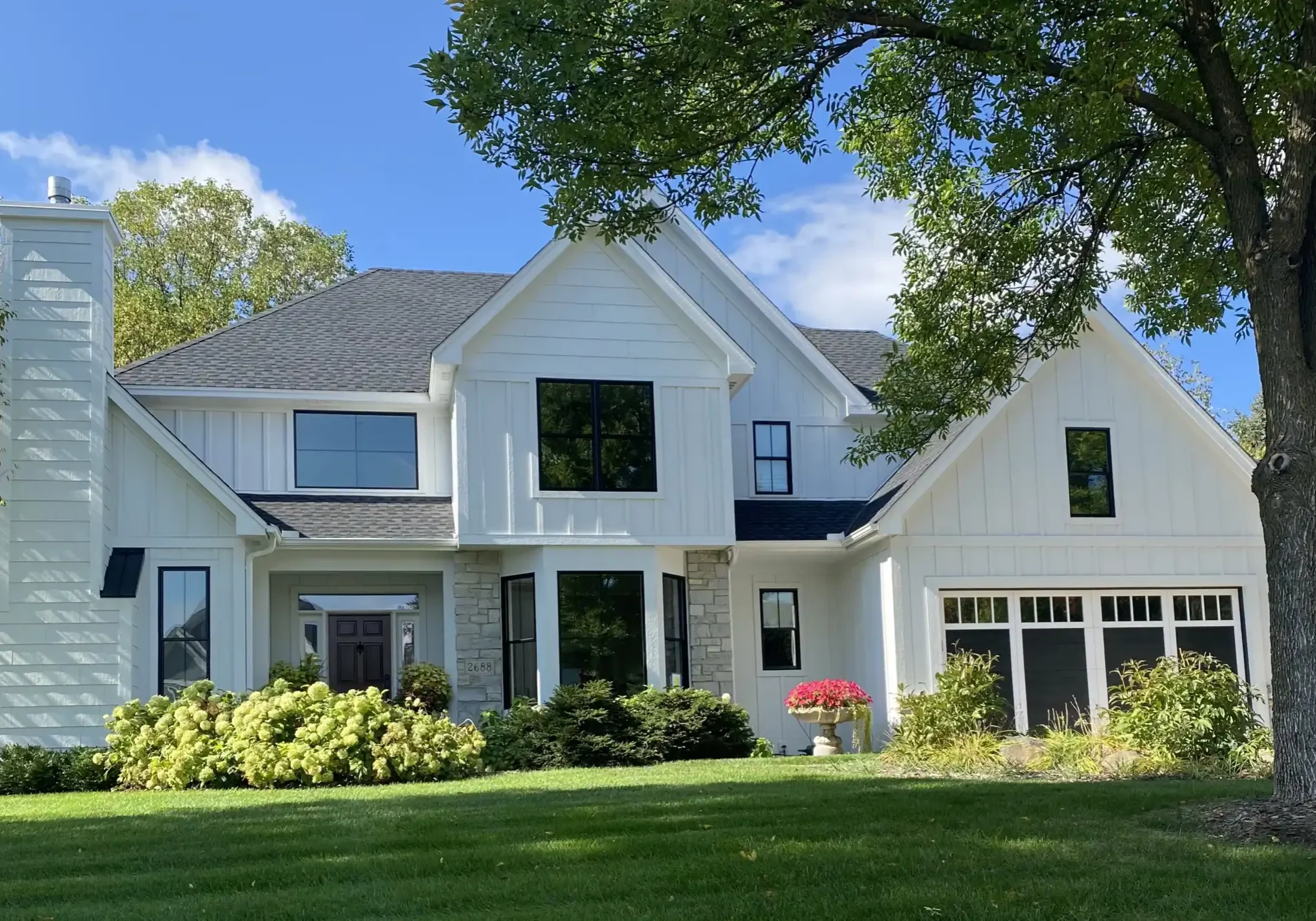 White modern farmhouse in Woodbury MN with new charcoal roof by Buildtec.